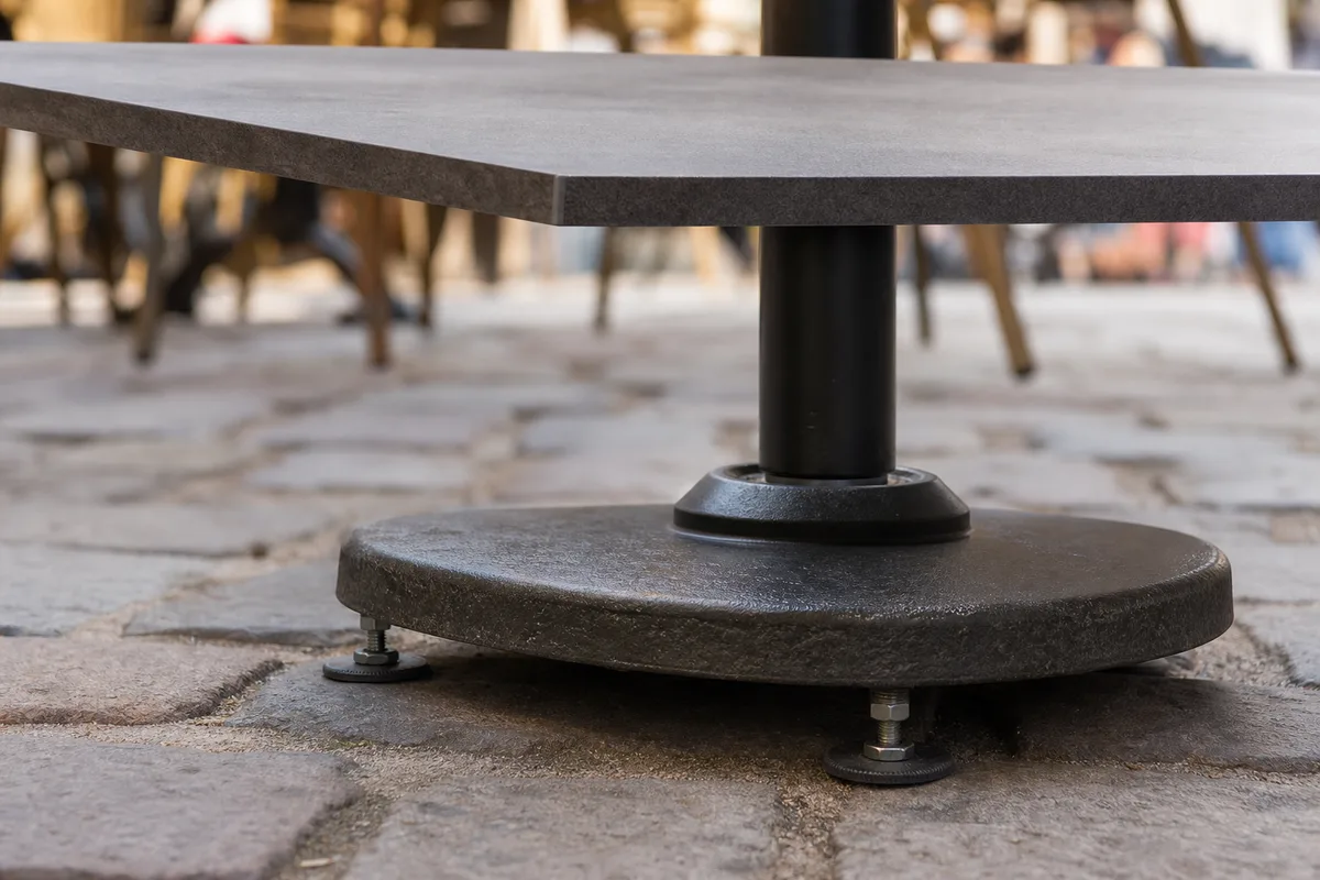 Gros plan sur un plateau de table bistrot et son pied central sur une terrasse